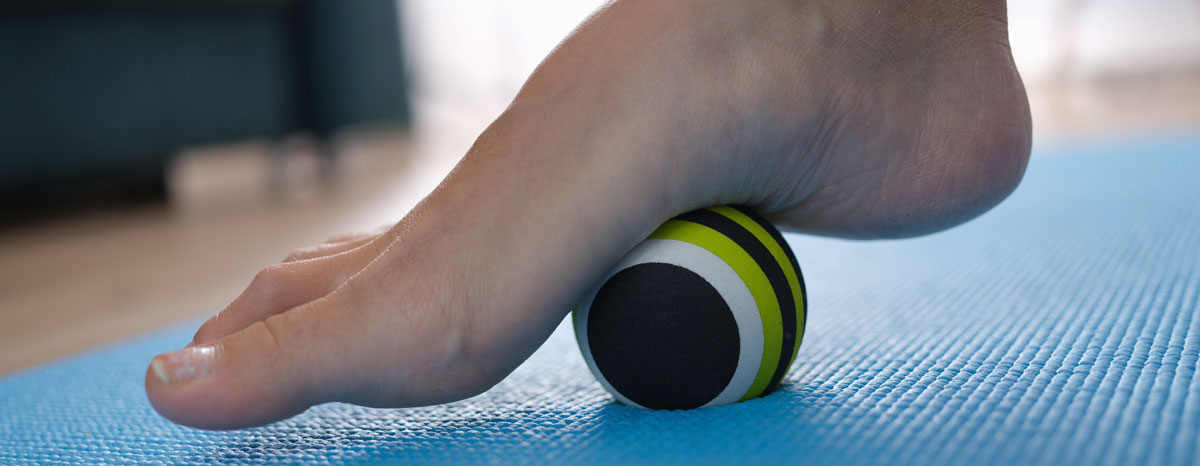 photo of someone rolling the arch of their bare foot on a ball