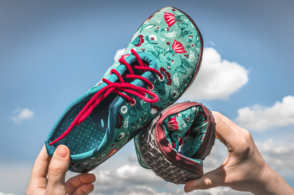 a photo of a pair of barefoot shoes where one shoe is rolled up showing the thin flexible sole
